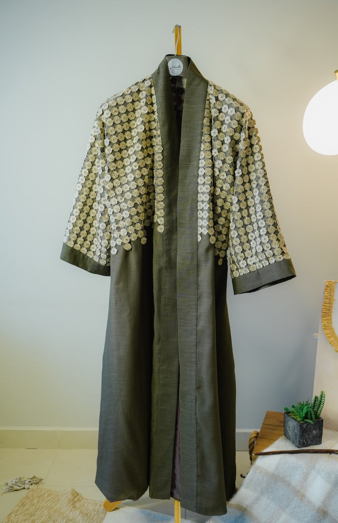 Olive green linen abaya with hand-worked stone lace and wide bisht sleeves.