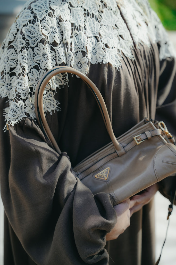 Model wearing a coco brown linen abaya featuring crochet lace, high neck, and pleated puff sleeves.