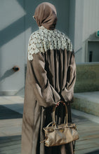 Load image into Gallery viewer, Model wearing a coco brown linen abaya featuring crochet lace, high neck, and pleated puff sleeves.